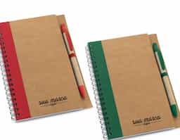 Caderno B6 espiral de capa dura em cartão, com 120 páginas lisas em papel reciclado e suporte para esferográfica (inclusa). 