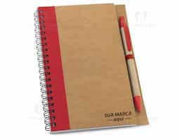 Caderno B6 espiral de capa dura em cartão, com 120 páginas lisas em papel reciclado e suporte para esferográfica (inclusa). 
