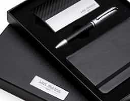 Kit executivo 3 peças. Acompanha: porta cartão de couro sintético texturizado com detalhes prata, caneta metal fosca com detalhe emborrachado preto, caderneta tipo moleskine em couro sintético com aproximadamente 80 folhas amarelas pautadas.