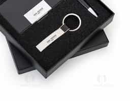 Kit executivo 3 peças em estojo de papelão com tampa e parte interna revestida de espuma. Contém: chaveiro metal fosco com detalhe em couro preto, porta cartão de couro sintético(verso metálico liso) com placa de metal e caneta metal fosca com detalhe emborrachado preto.