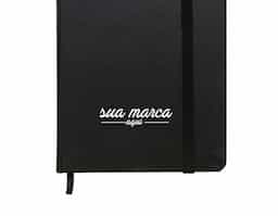 Caderneta brochura tipo moleskine com capa dura e marca página de cetim, contém aproximadamente 80 folhas amareladas com pauta.