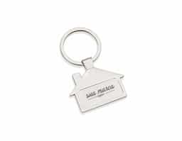 Chaveiro metal brilhante formato casa. Parte frontal com desenho em relevo das janelas e portas, verso com um retângulo no centro, ideal para personalização.