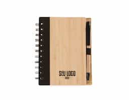 Bloco de anotações ecológico com caneta. Capa de bambu com uma faixa preta no lado esquerdo da capa e verso liso. Possui aproximadamente 70 folhas brancas pautadas com logo reciclado na lateral inferior. Acompanha suporte elástico de nylon com uma caneta de papelão de detalhes plásticos.