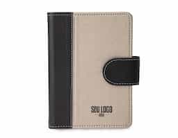 Caderneta de couro sintético com fechamento de botão. Possui caderno capa dura em couro sintético com aproximadamente 100 folhas pautadas, divisórias para cartões e bolso lateral.