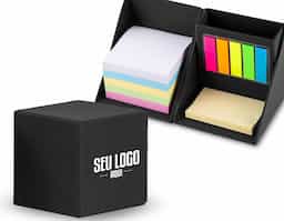 Bloco de anotações formato cubo com autoadesivos, abre e fecha em diagonal. Possui 5 blocos autoadesivos com aproximadamente 20 folhas cada, bloco amarelo com aproximadamente 50 folhas e conjunto de blocos com 4 cores e aproximadamente 100 folhas cada. Possui suporte para caneta, clips e afins no compartimento atrás bloquinhos coloridos.