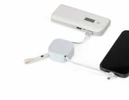Cabo USB retrátil com suporte para celular. Contém entradas Lightning/iPhone, V8/Android, Tipo-C/Android e 4 diferentes ajustes do comprimentos dos cabos. Suporte de frente lisa e com alça para transporte em couro sintético.