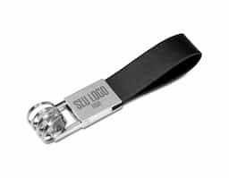 Chaveiro de metal com 4 argolas e alça em couro sintético, possui “mosquete” giratório (para utilização basta levantá-lo e rotacionar). Metal brilhante com frente lisa e verso com um parafuso inferior.