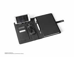 Pasta A5 em 300D poliéster reciclado (100% rPET) com carregador wireless embutido. A bateria tem capacidade para 5.000 mAh, potência de 10W, entrada/saída 5V/2.1A e cabo USB tipo C para carregar a bateria. A pasta contém no seu interior um bolso para smartphone até 6.5'', três espaços para cartões, quatro luzes LED, botão on/off, suportes para esferográfica (não inclusa), celular e cabo USB, um bloco de notas com capa em cartão preto e 64 folhas pautadas de cor marfim, em papel proveniente de gestão florestal sustentável. Na frente existe ainda uma impressão oval em preto para indicar a área de carga do wireless. Fornecido em caixa presente. 165 x 225 x 25 mm