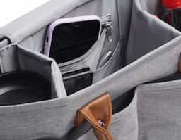 Bolsa Multifuncional em poliéster 300D com detalhes em PU e interior em 210D, possui 5 compartimentos externos. Conta com alças de ombro e mão em PU, engate para carrinho de bebê e velcro para fechamento interno. O interior oferece 5 divisórias removíveis, sendo uma com zíper e uma com tecido térmico, proporcionando praticidade e organização.