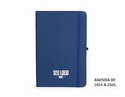 Planner com capa dura emborrachada, marca-páginas em fita de cetim, elástico para fechamento e suporte para caneta. Apresenta páginas dedicadas a dados pessoais, calendários de 2025 até 2027 e espaço para anotações diárias e semanais ao longo de todo ano de 2026.