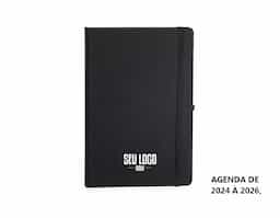 Planner com capa dura em cromato, marca-páginas em fita de cetim, elástico para fechamento e suporte para caneta. Apresenta páginas dedicadas a dados pessoais, calendários de 2025 a 2027 e espaço para anotações diárias e semanais ao longo de todo o ano de 2026.