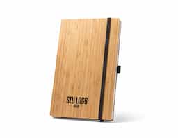 Caderno A5 de capa e contracapa em placa de bambu e lombada em poliéster 100% reciclado (100% rPET). O interior contém 96 folhas pautadas com papel reciclado, suporte para esferográfica (não inclusa) e elástico para fecho do caderno. A cor e o resultado da impressão nos materiais naturais pode variar entre produtos. 140 x 210 mm