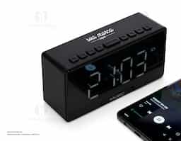 Caixa de som multimídia com relógio despertador e suporte para celular. Produzida em plástico e com borrachas antiderrapantes na área inferior, a caixa de som tem a área frontal com display de LED, além de um compartimento com suporte para celular – uma espécie de "gaveta" aonde é exibido (MUSIC), basta puxá-la ter acesso ao compartimento. A caixa de som executa nos modos bluetooth, rádio FM, cartão TF-microSD e entrada auxiliar P2. Acompanha cabo USB e manual em inglês.