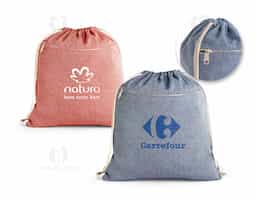 Sacola tipo mochila em 70% algodão reciclado e 30% poliéster reciclado (140 g/m²), com bolso frontal, fecho discreto e alças em algodão. O tecido é sem tingimento, é utilizado na sua cor original, sem produtos químicos de tingimento ou branqueamento, contribuindo para um menor impacto ambiental.