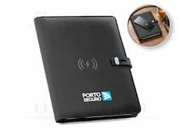 Pasta A5 em 300D poliéster reciclado (100% rPET) com carregador wireless embutido. A bateria tem capacidade para 5.000 mAh, potência de 10W, entrada/saída 5V/2.1A e cabo USB tipo C para carregar a bateria. A pasta contém no seu interior um bolso para smartphone até 6.5'', três espaços para cartões, quatro luzes LED, botão on/off, suportes para esferográfica (não inclusa), celular e cabo USB, um bloco de notas com capa em cartão preto e 64 folhas pautadas de cor marfim, em papel proveniente de gestão florestal sustentável. Na frente existe ainda uma impressão oval em preto para indicar a área de carga do wireless. Fornecido em caixa presente. 165 x 225 x 25 mm