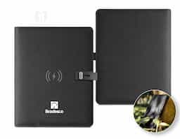 Pasta A5 em 300D poliéster reciclado (100% rPET) com carregador wireless embutido. A bateria tem capacidade para 5.000 mAh, potência de 10W, entrada/saída 5V/2.1A e cabo USB tipo C para carregar a bateria. A pasta contém no seu interior um bolso para smartphone até 6.5'', três espaços para cartões, quatro luzes LED, botão on/off, suportes para esferográfica (não inclusa), celular e cabo USB, um bloco de notas com capa em cartão preto e 64 folhas pautadas de cor marfim, em papel proveniente de gestão florestal sustentável. Na frente existe ainda uma impressão oval em preto para indicar a área de carga do wireless. Fornecido em caixa presente. 165 x 225 x 25 mm