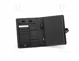 Pasta A5 em 300D poliéster reciclado (100% rPET) com carregador wireless embutido. A bateria tem capacidade para 5.000 mAh, potência de 10W, entrada/saída 5V/2.1A e cabo USB tipo C para carregar a bateria. A pasta contém no seu interior um bolso para smartphone até 6.5'', três espaços para cartões, quatro luzes LED, botão on/off, suportes para esferográfica (não inclusa), celular e cabo USB, um bloco de notas com capa em cartão preto e 64 folhas pautadas de cor marfim, em papel proveniente de gestão florestal sustentável. Na frente existe ainda uma impressão oval em preto para indicar a área de carga do wireless. Fornecido em caixa presente. 165 x 225 x 25 mm