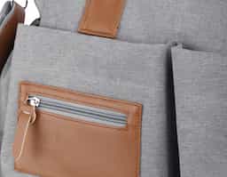 Mochila funcional em poliéster e couro sintético, equipada com compartimento principal com divisórias para organização. Possui alças de ombro e de mão, além de quatro bolsos laterais para armazenamento adicional. Ideal para uso diário e versátil.