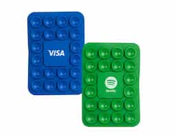 Libere o uso das mãos e utilize nossa ventosa para fixar celulares em superfícies lisas. Produzida em PVC flexível, conta com 20 ventosas que garantem a fixação dos celulares em superfícies como mesas, espelhos, janelas e até no carro, sem a necessidade de ferramentas extras. Basta remover o adesivo 3M, colá-lo no celular e fixá-lo na superfície. Além de sua praticidade, o suporte oferece um espaço exclusivo para personalização, tornando-se uma excelente opção para divulgar a marca do cliente.