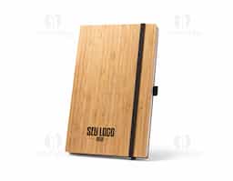 Caderno A5 de capa e contracapa em placa de bambu e lombada em poliéster 100% reciclado (100% rPET). O interior contém 96 folhas pautadas com papel reciclado, suporte para esferográfica (não inclusa) e elástico para fecho do caderno. A cor e o resultado da impressão nos materiais naturais pode variar entre produtos. 140 x 210 mm