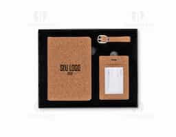 Kit viagem com 3 peças composto por porta-passaporte e tag identificadora de bagagem com alça, ambos com acabamento em cortiça. Acondicionado em estojo de papel com berço espumado e revestido em veludo, oferece praticidade e segurança na identificação de itens durante viagens.