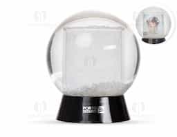 Globo de neve em plástico resistente, com glitter interno e porta-foto. A base preta é removível para inserção de uma foto no suporte interno, com dimensões de 8,5 cm x 4,7 cm, unindo decoração e funcionalidade em um só item.