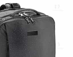 Mochila de viagem em poliéster reciclado 600D com acabamento repelente à água e forro em poliéster reciclado 210D. Possui três compartimentos principais: traseiro com bolsos para notebook até 17.3" e tablet até 10.1", central expansível para roupas e frontal com divisórias internas. Conta com três bolsos externos, dois com forro em PEVA, placa metálica removível, alças ajustáveis, cintas de compressão, pegas almofadadas e alça para trolley. Capacidade até 29 L.