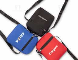 Mini bolsa confeccionada em tecido resistente à água e alça transversal ajustável em nylon. Possui fechamento em zíper e bolso frontal que facilita a organização de objetos.
