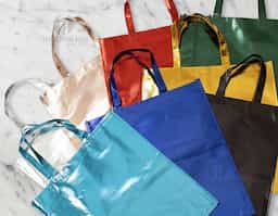 Sacola em TNT com revestimento externo laminado, que oferece maior resistência e durabilidade. Possui duas alças costuradas, garantindo segurança no transporte. Leve, reutilizável e prática, é ideal como brinde corporativo para eventos, feiras e ações promocionais.